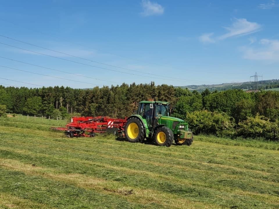 The sun shining in the summer months with a John Deere and Lely Hibiscus 915d rake 