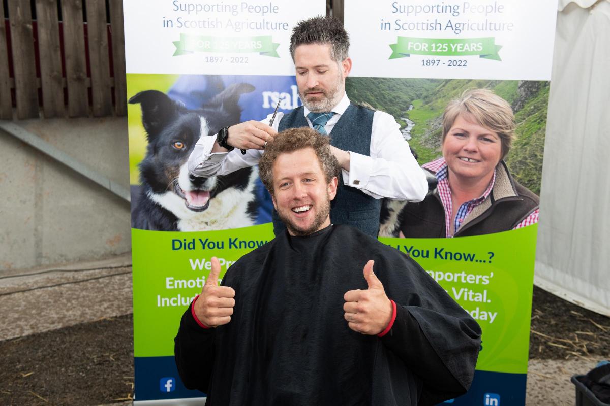 Kilted Barber Campbell Ewen takes a bit of the the top for Cammy Wilson in aid of RSABI Ref:RH010622114  Rob Haining / The Scottish Farmer...