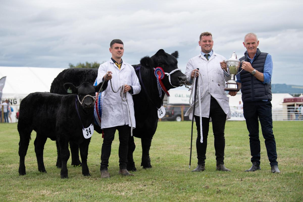 Simon Simmers presents the Scottish Beef Supreme Cattle Championship trophy to Mark Wattie and Liam Robertson holding the calf  Ref:RH080822055  Rob Haining / The Scottish Farmer...